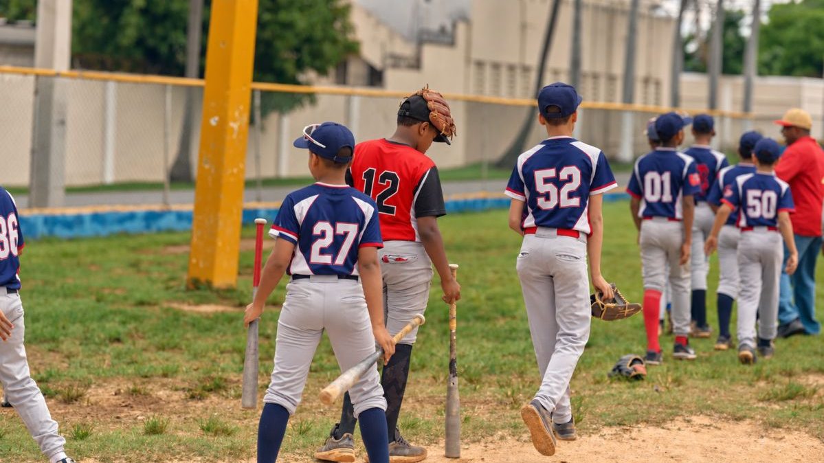 Jóvenes prospectos dominicanos entrenando béisbol en una academia con guantes y bates