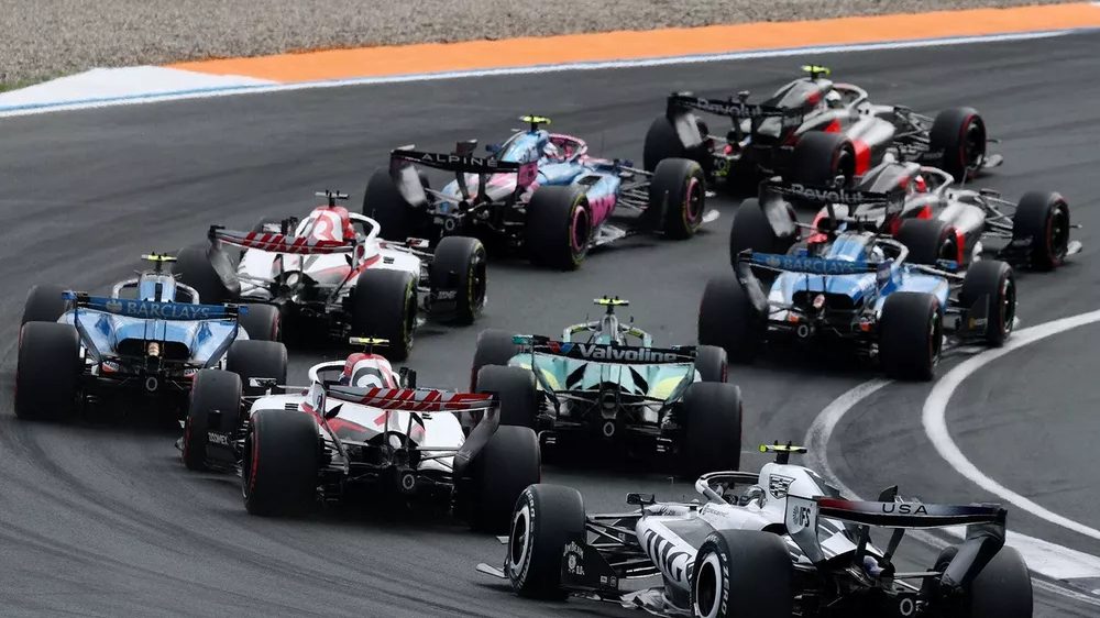 Monoplazas de Fórmula 1 en pista durante una carrera, con el fondo de un circuito lleno de público