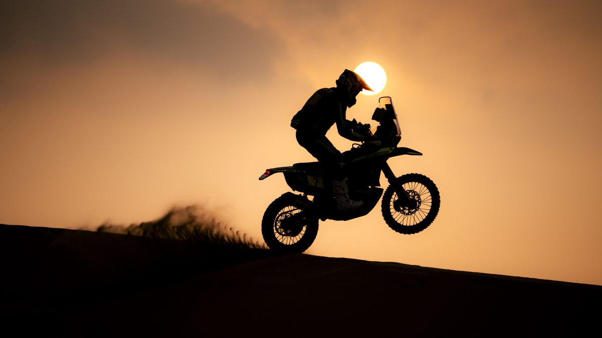 Vehículo del Rally Dakar rodando en desierto de Marruecos con dunas al fondo