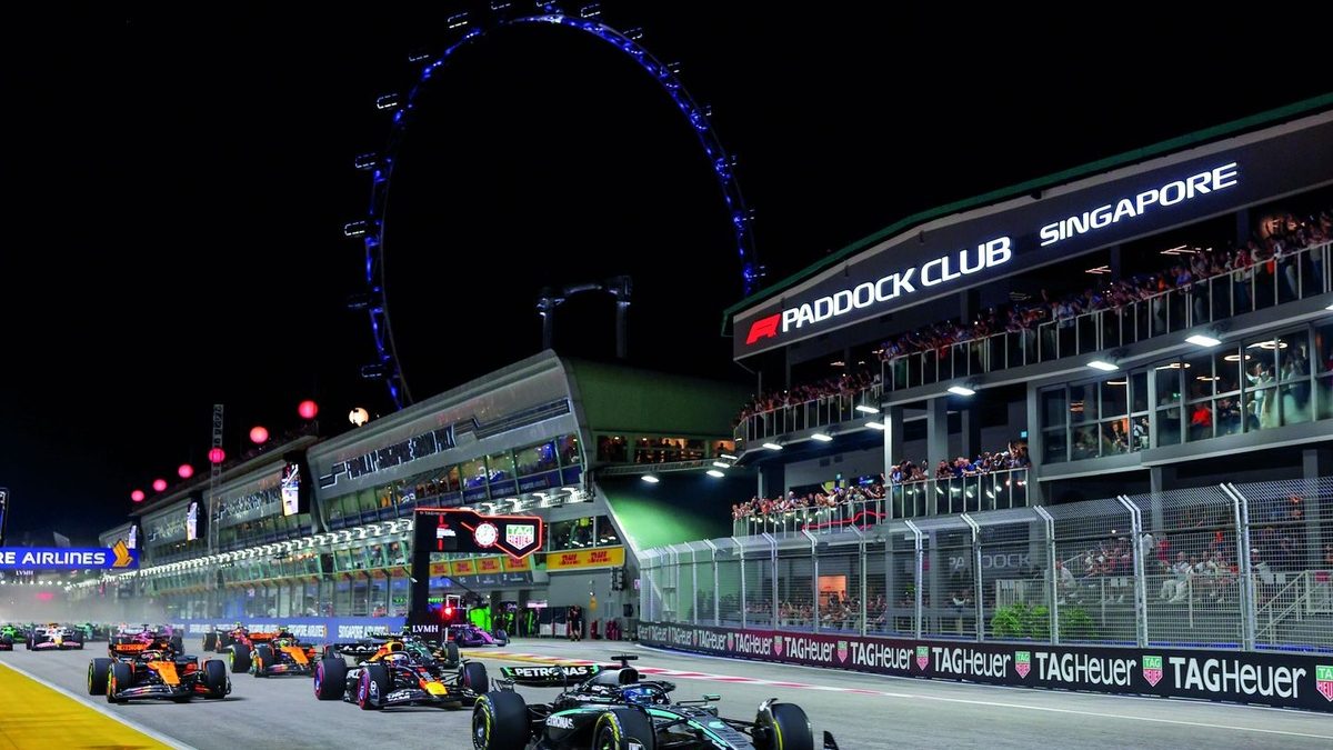 Monoplazas de Fórmula 1 compitiendo de noche en el circuito callejero de Singapur con las luces de la ciudad de fondo