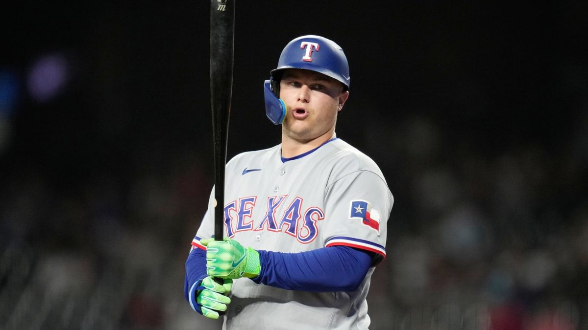 Joc Pederson con el uniforme de los Rangers de Texas sosteniendo su mano izquierda lesionada durante un partido de MLB