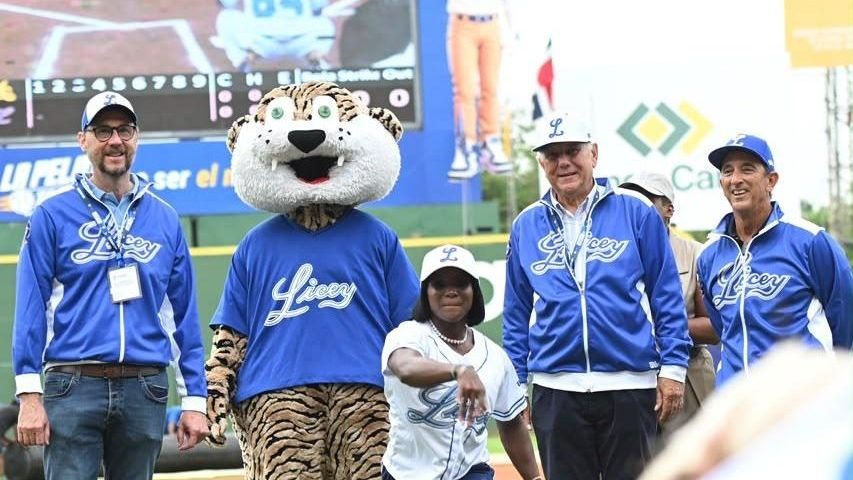 Velocista dominicana Liranyi Alonso lanzando la primera bola en el Estadio Quisqueya Juan Marichal con directivos del Licey