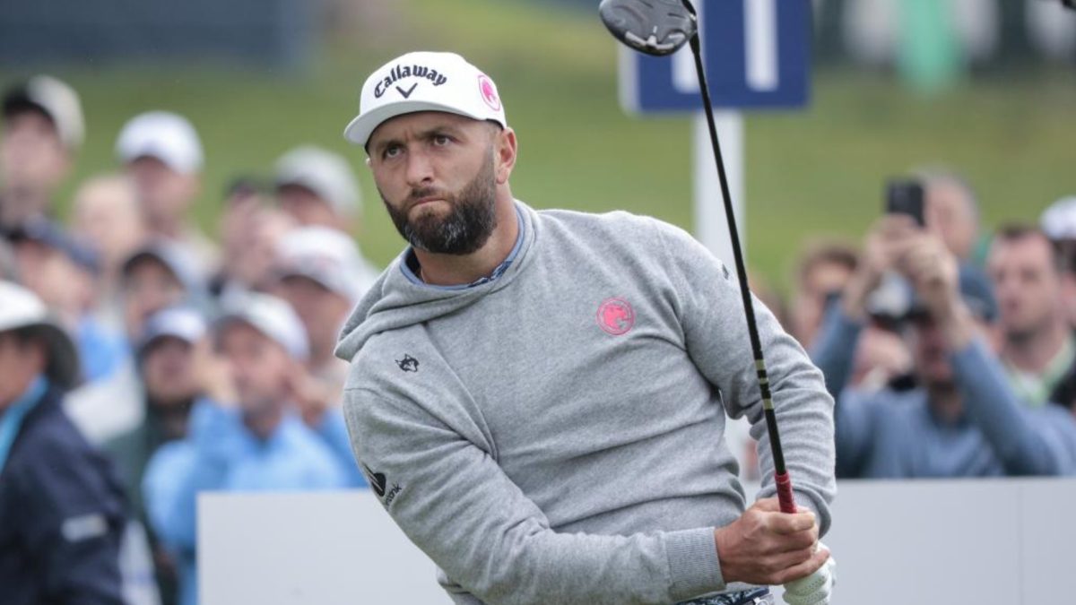 Jon Rahm golpeando una bola durante un torneo del LIV Golf con el logo del circuito al fondo