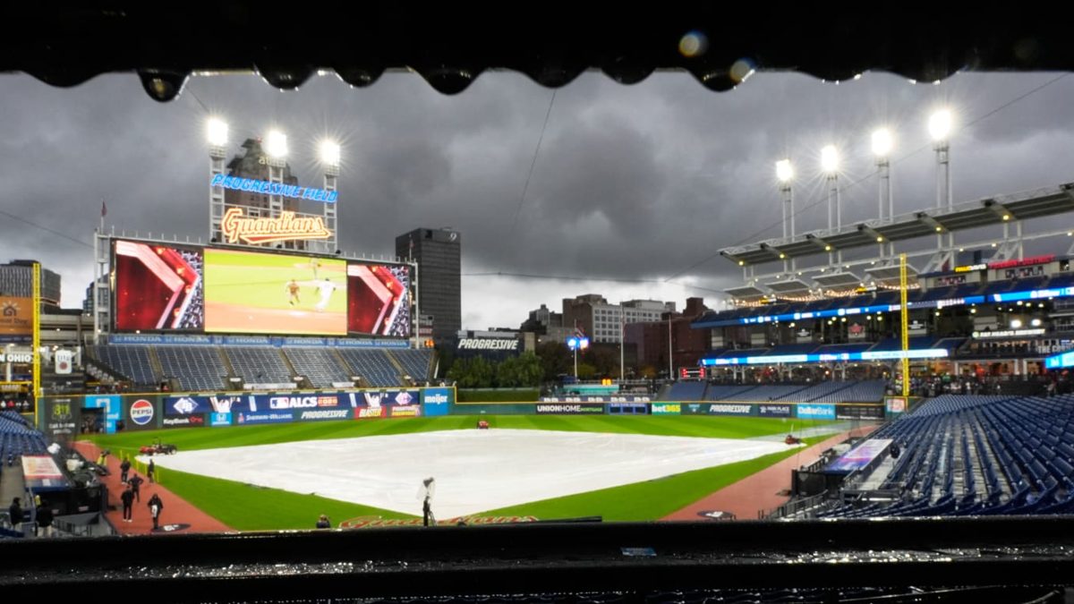 Grounds crew de Cleveland retirando agua de la lona del infield en Progressive Field durante la lluvia que pospuso el Juego 4 de la ALCS